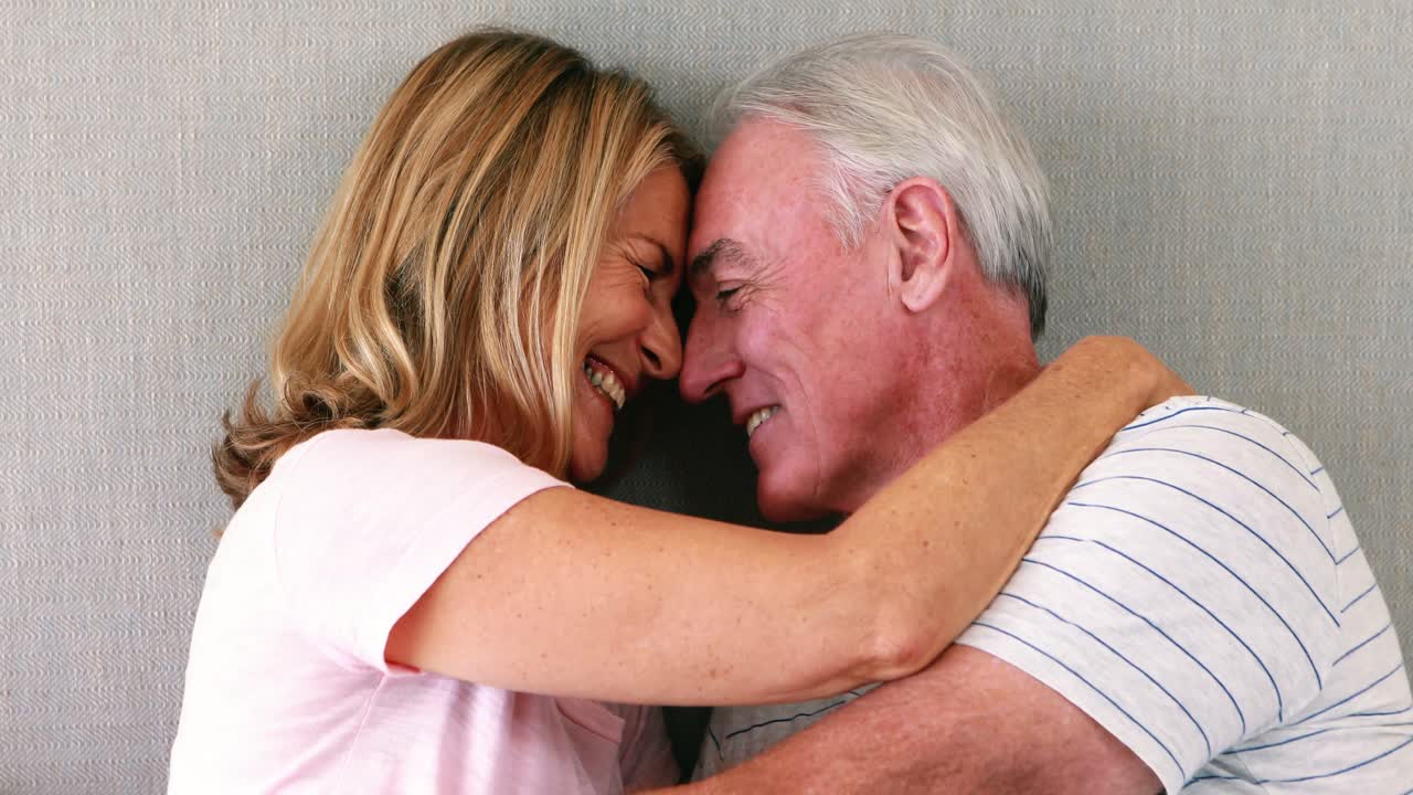 pareja de ancianos felices interactuando entre sí en la cama