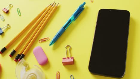 video of composition of diverse office tools and smartphone with copy space on yellow background