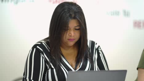 Serious-black-woman-working-on-laptop-in-office