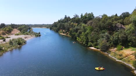 Toma-Aérea-De-Personas-Que-Viajan-En-Kayaks-Y-Embarcaciones-Personales-Inflables-En-El-Río-Americano-En-Sacramento,-California