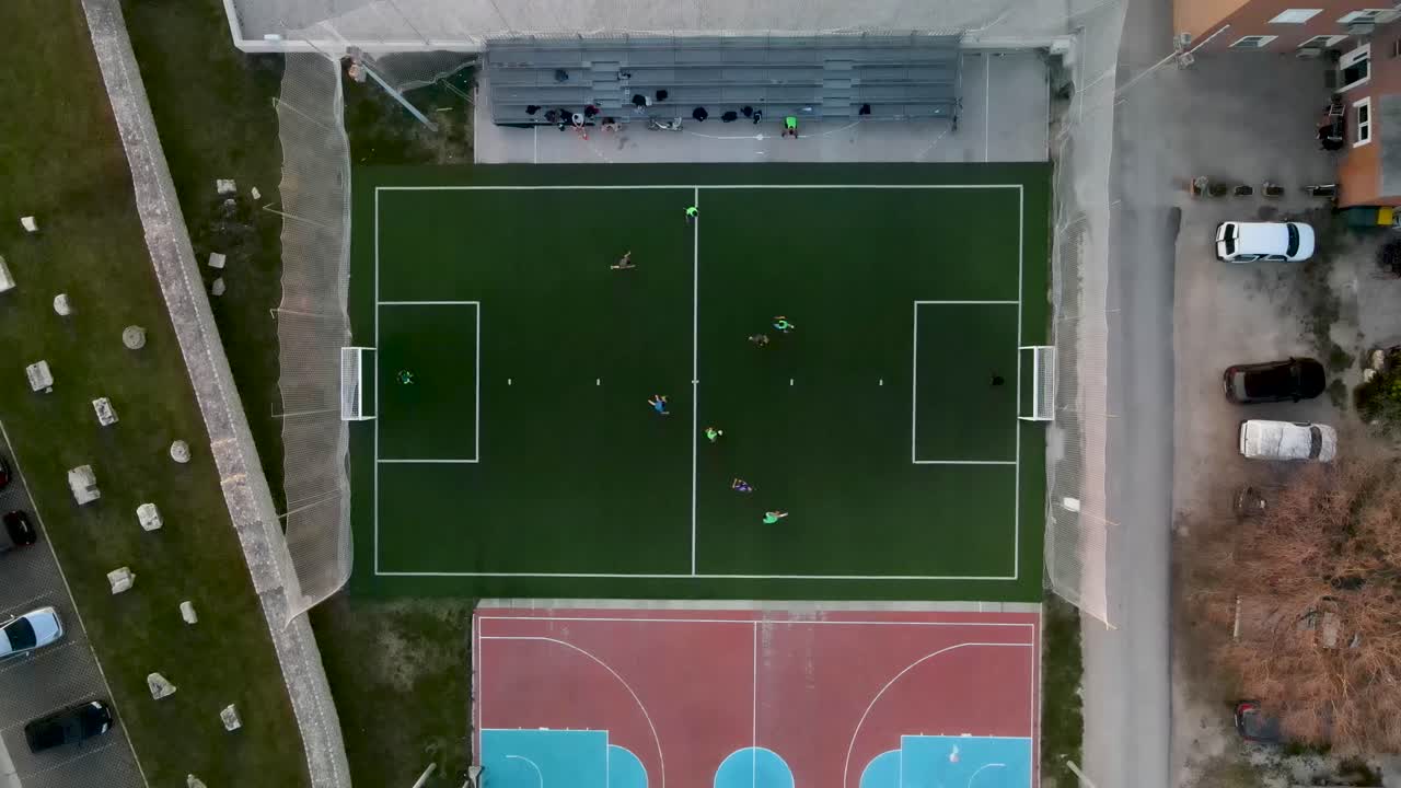 полет беспилотника с высоты птичьего полета над небольшим футбольным полем, на котором проходит игра