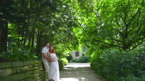 pregnant couple hugging in park at summer. expecting parents hugging at park