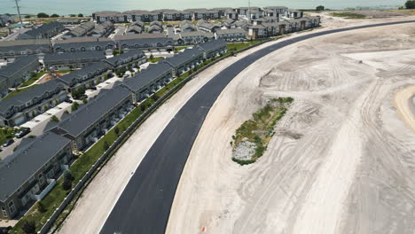 aerial view flying down long curved tarmac road and pristine new suburban real estate development in utah