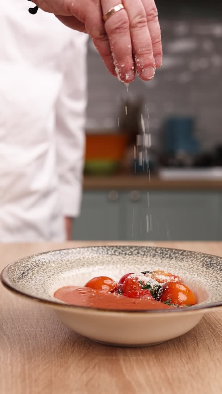 chef preparando un plato de sopa de tomate con queso parmesano