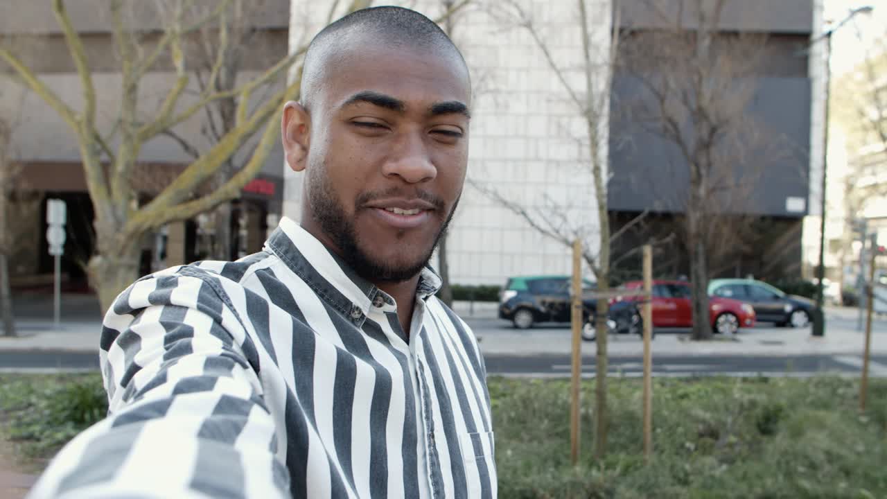 hombre afroamericano guapo y alegre grabando un mensaje de video