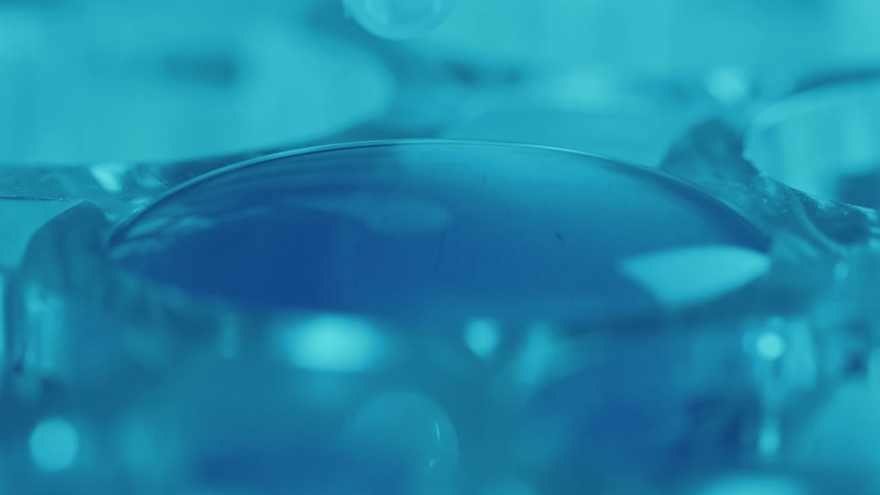 Colorless Liquid Dripping into Well of Laboratory Microplate