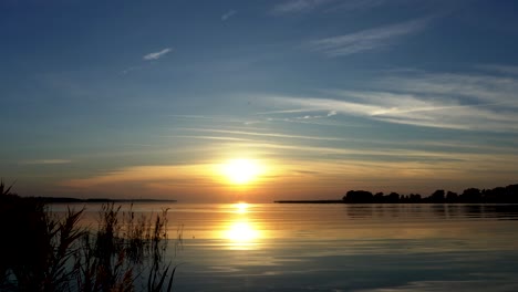 Tiro-Medio-Ancho-De-La-Puesta-De-Sol-Sobre-El-Mar-Con-Cielo-Azul