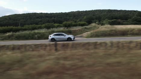 Honda-Civic-driving-rural-road-passing-vineyards-in-Provence,-France,-aerial