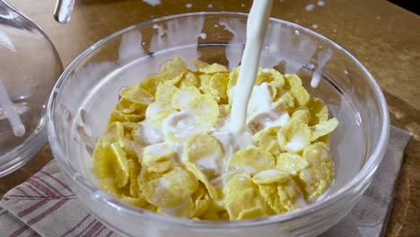 crispy yellow corn flakes into the bowl for the morning a delicious breakfast with milk. slow motion with rotation tracking shot.