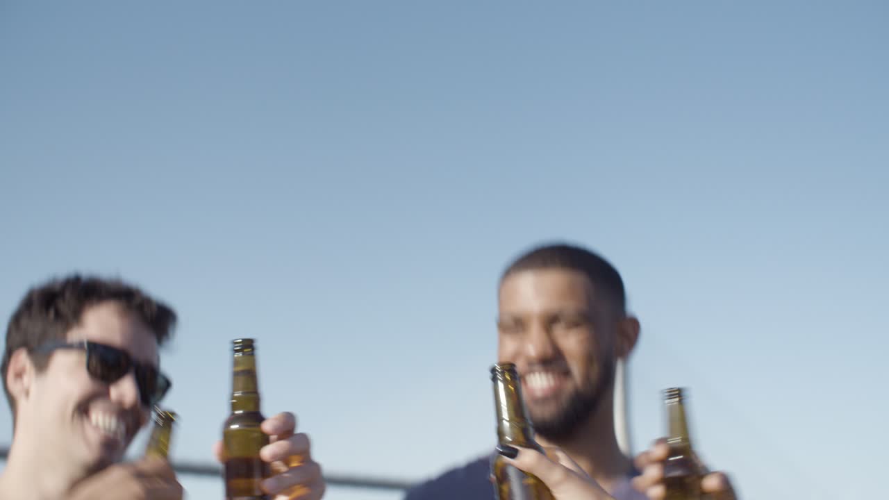 amigos sonrientes haciendo sonar botellas de cerveza durante las vacaciones