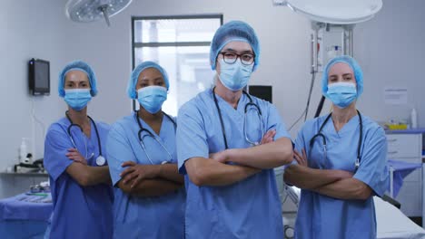 Portrait-of-diverse-female-and-male-surgeons-wearing-face-masks-and-scrubs-in-hospital