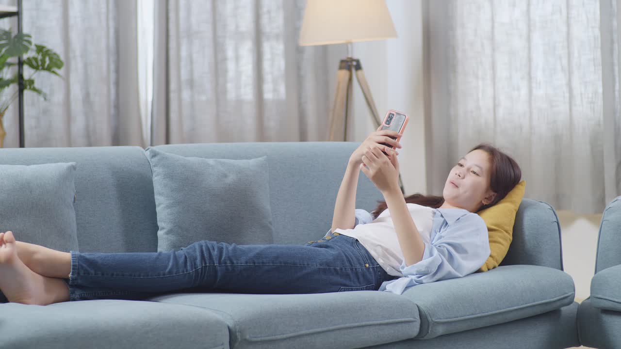 스마트폰을 사용하여 소파에서 휴식을 취하는 여성