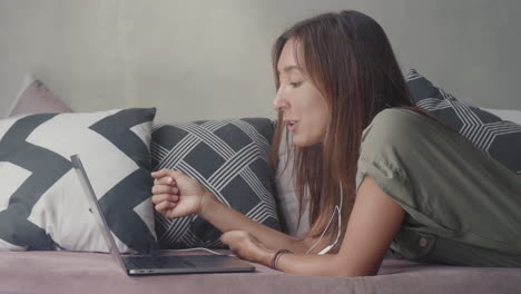 woman using laptop lying on couch