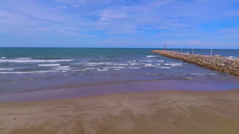 Ich-Schwenke-Mit-Einer-Drohne-Vom-Strand-Und-Dem-Wellenbrecher,-Der-Das-Meer-Und-Den-Fluss-Japa-In-Boca-De-Rio-Trennt