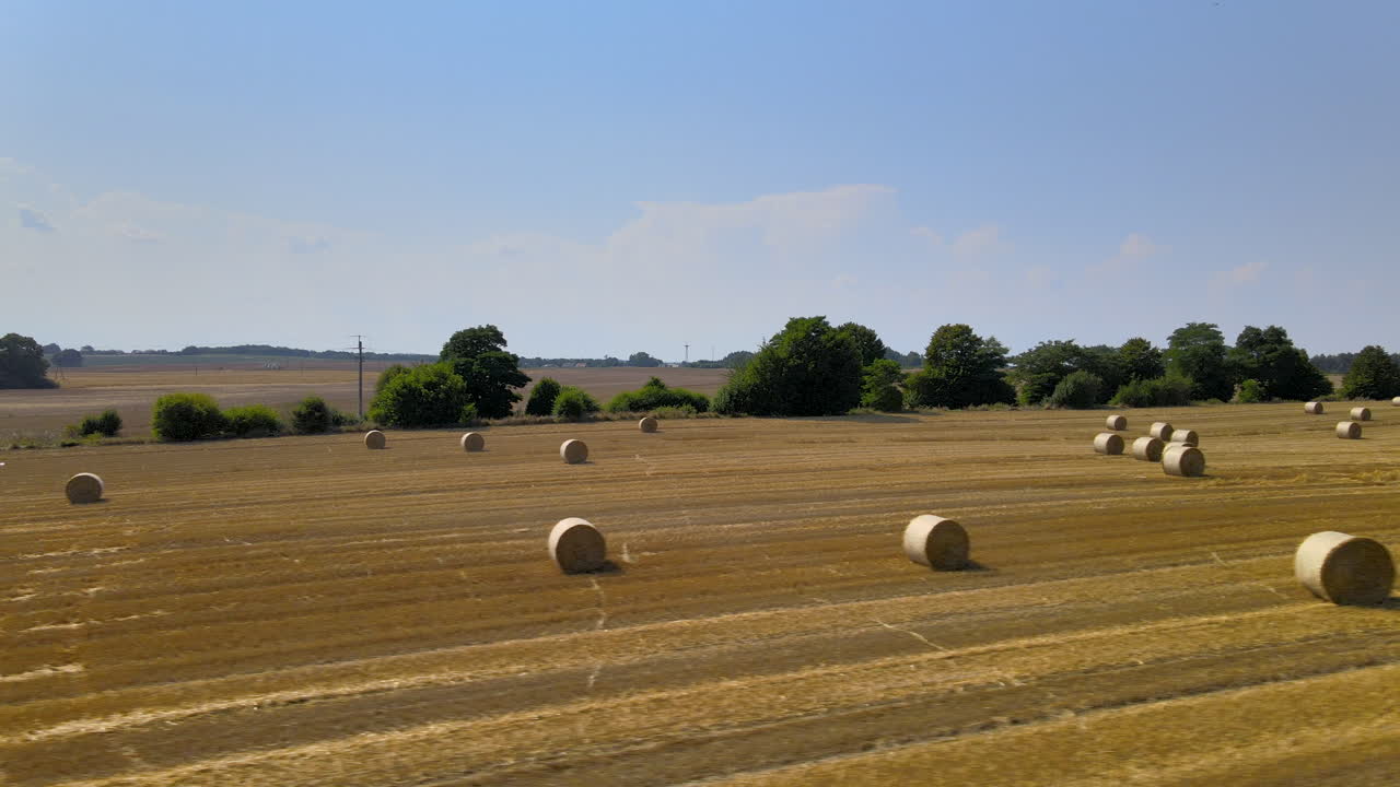 Golden hay field with round hay bales aerial truck shot of flat rural farmland