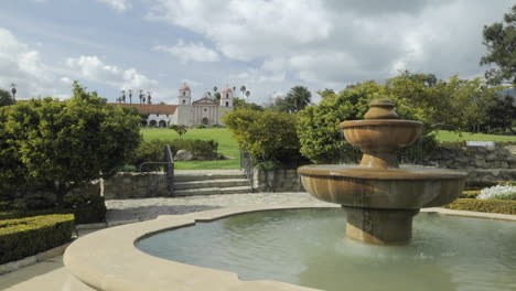 Time-lapse-dolly-shot-of-clouds-passing-over-the-Mission-Santa-Barbara-in-front-of-the-rose-garden-fountain-in-Santa-Barbara-California