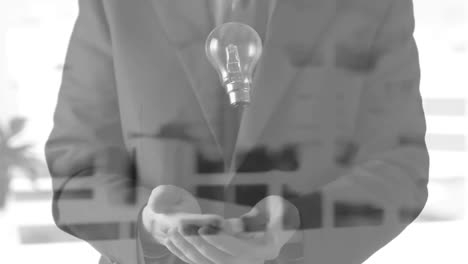 animation of light bulb over businessman hands in office background