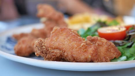 close up of crispy chicken tenders with side salad