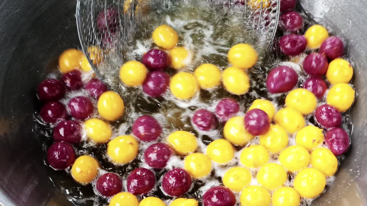 Watch vibrant grape tomatoes fry in hot oil creating a culinary spectacle in a bustling kitchen.
