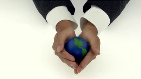 a pair of cupped hands holds a small globe