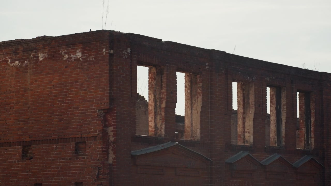 Bela fachada de tijolos desgastados com aberturas de janelas vazias, argamassa desmoronando e linha do telhado enferrujada sob a luz suave do crepúsculo, atmosfera melancólica, textura granulada, silhueta urbana desolada, industrial histórico