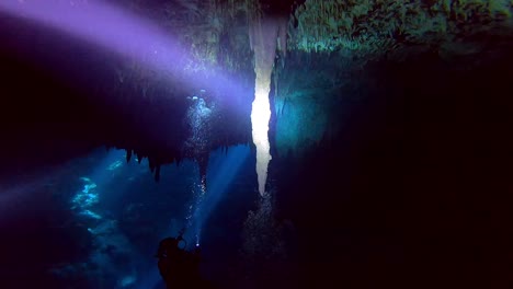 stalattiti in una grotta con subacqueo e luce