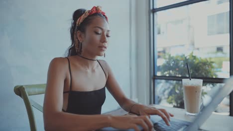 mujer trabajando en una computadora portátil en un café