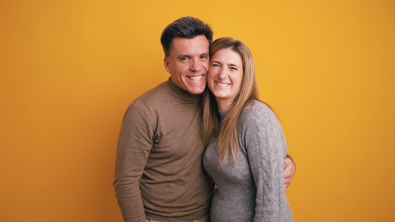 Casal feliz abraçando-se e sorrindo em fundo amarelo