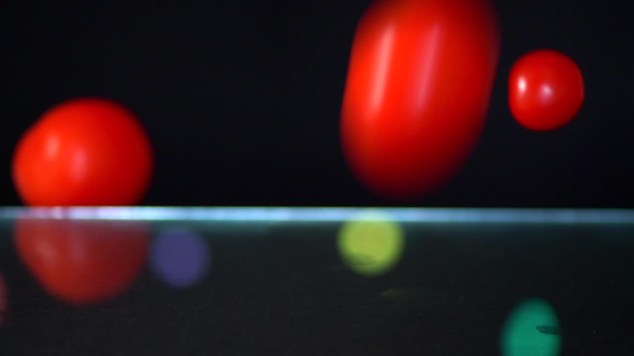 덩굴 익은 토마토와 체리 토마토가 섞인 느린 동작이 멀리 있는 요정 불빛과 함께 검은 배경의 프레임에 떨어지는 것