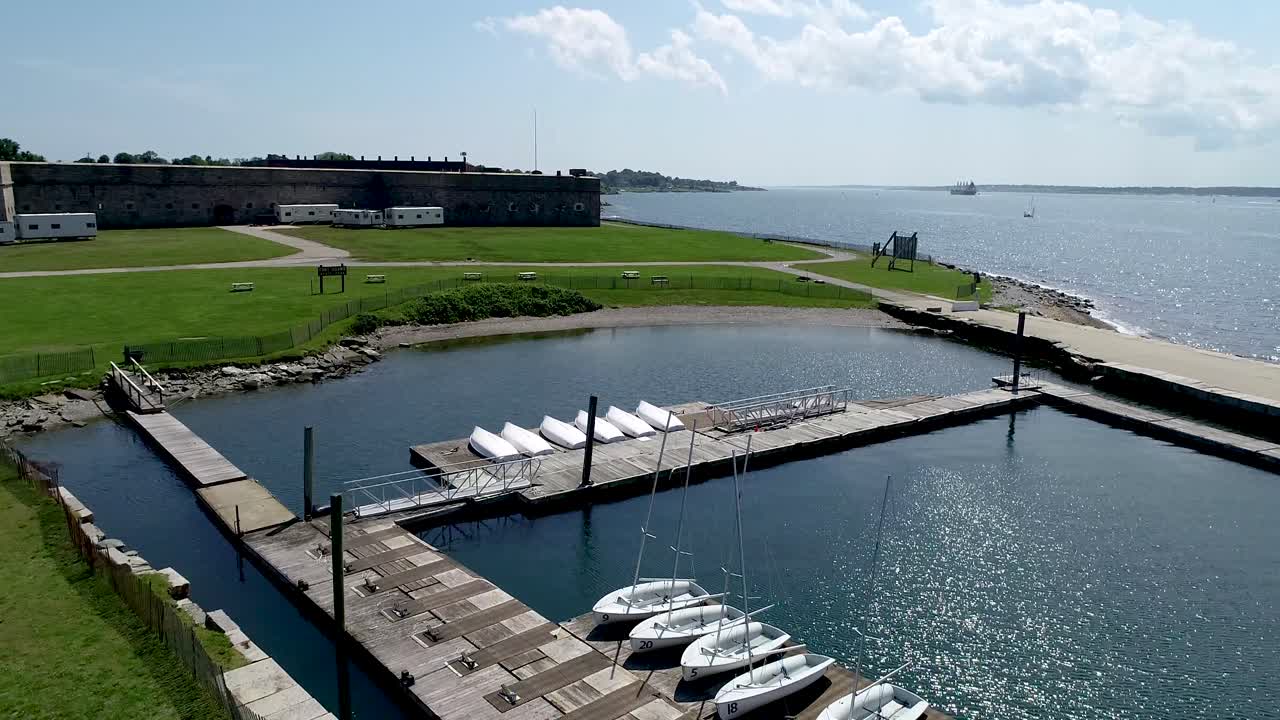 En drönare flyger över den diagonala udden av Newport Rhode Islands bukt nära Fort Adams för att avslöja bryggor och vatten som öppnar sig mot havet