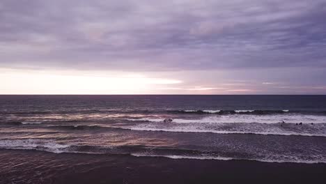 people walking on the purple olon beach of ecuador at sunset -aerial