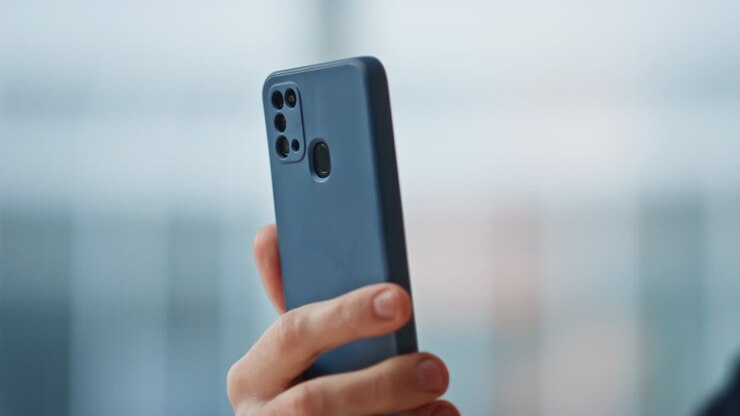 Primo piano di un manager allegro che legge SMS sul cellulare seduto in ufficio. Uomo sorridente.