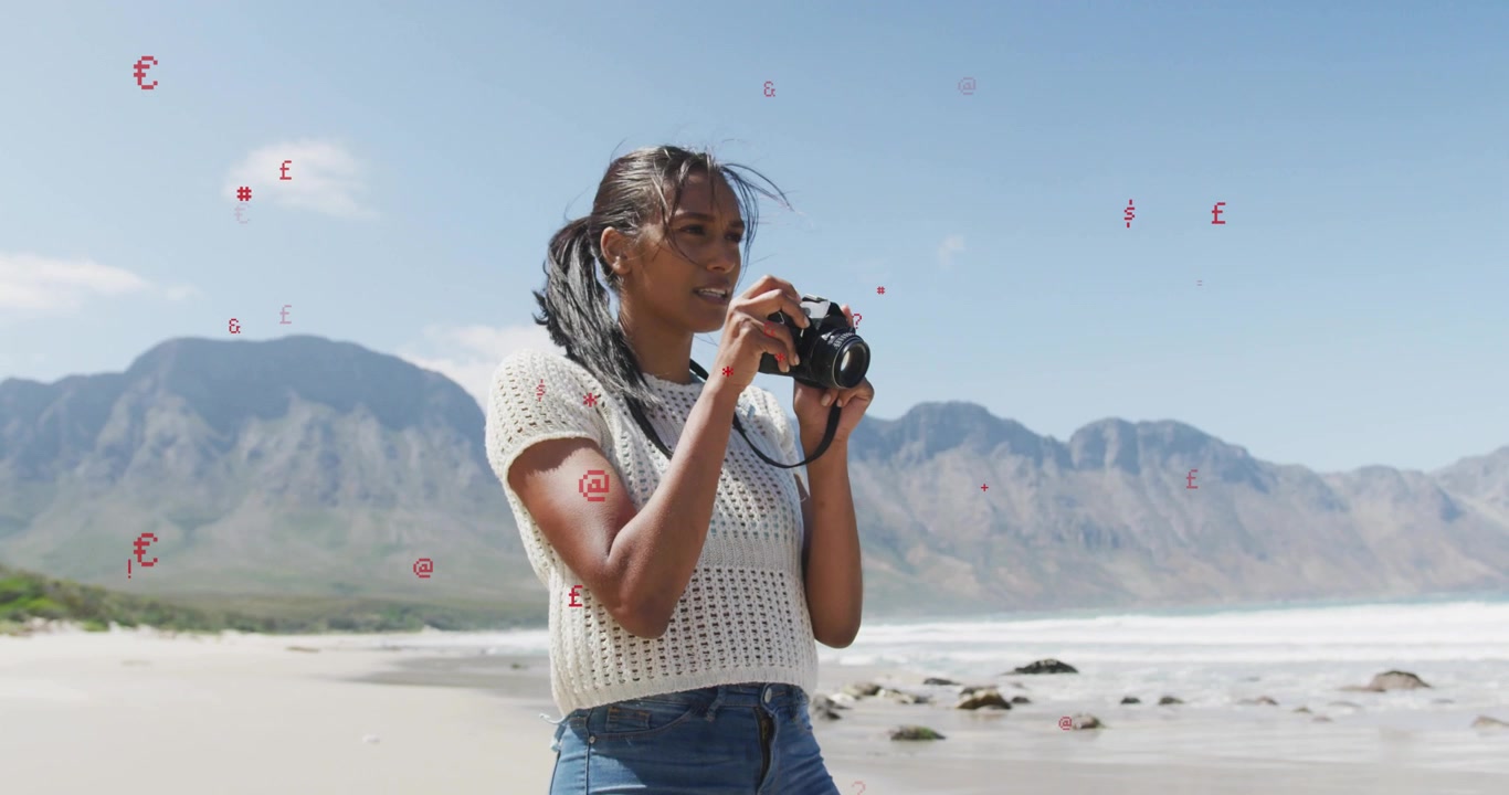 Woman raising DSLR to eye, doing travel photography on beach, checking settings and composing waves