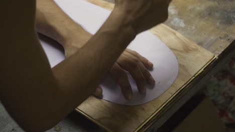 hands of man outlining shape of a diy skateboard project on wooden plank