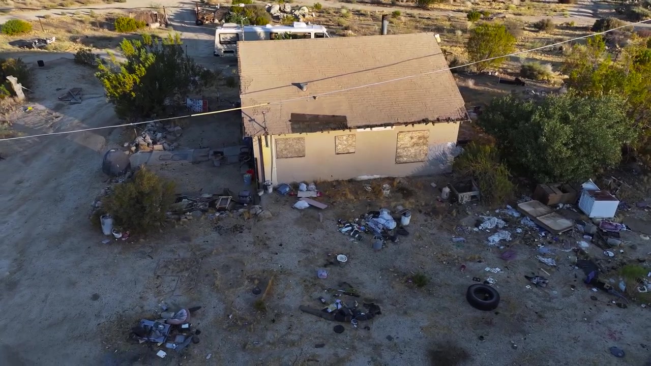 Accampamento di senzatetto ed edifici abbandonati a Palm Wells, California, illuminati dall'alba mattutina. Carrellata aerea.