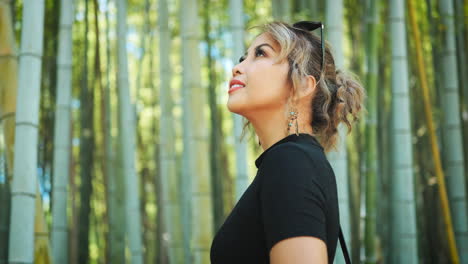primer plano de una mujer mirando hacia arriba en un bosque de bambú, con la luz del sol filtrando a través de los tallos altos