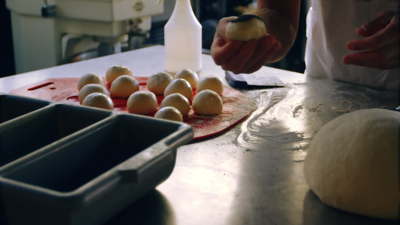 Male chef applying poppy seeds on rolled dough balls 4k