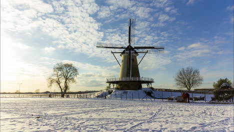 time lapse of clouds passing over traditional windmill in beautiful white winter rural landscape