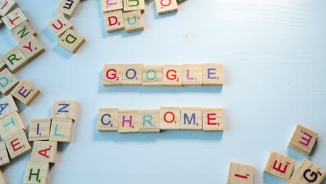 una persona deletreando google chrome en una mesa con letras de madera dispersas