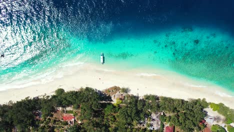 isla en el caribe - barco atracado en la costa de arena blanca de una exuberante isla con arrecifes de coral vistos a través del agua azul clara del océano - un hermoso destino turístico - toma aérea