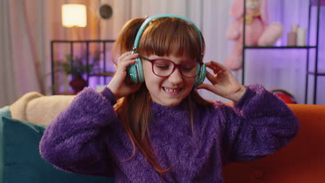 Una-Adolescente-Feliz-Con-Auriculares-Inalámbricos-Relajándose-Sentada-En-Un-Sofá-En-Casa-Escuchando-Su-Música-Favorita