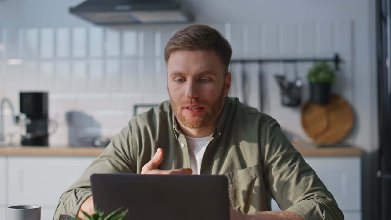Smiling man video calling laptop in home kitchen closeup. Happy freelancer work