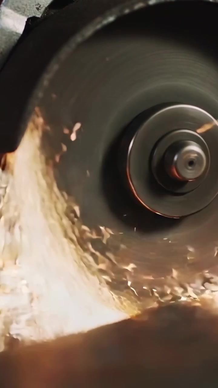 Vertical video: Sparking rotating wheel contacting metal workpiece at workbench, sharpening metal