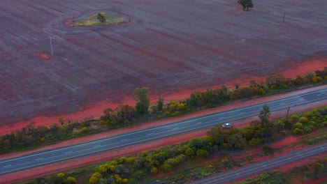 scenic view of an isolated vehicle on outback countryside highway near alice springs, northern territory in australia