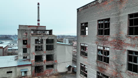 damaged ruins of past big plant. forlorn wrecked emptied buildings with no windows and old brick walls. blue clear sky at the background.