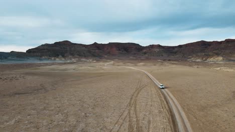 Drone-Vuela-Sobre-Un-Automóvil-Que-Conduce-A-Través-De-Una-Montaña-Humeante-Hacia-El-Punto-Alstrom,-Lago-Powell