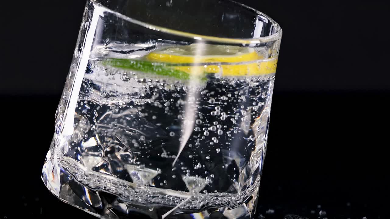 A detailed view of a sparkling drink with lime and lemon slices in a crystal glass.