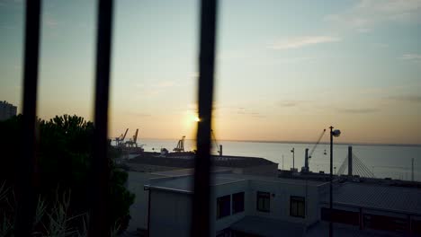 lisbon harbor sunrise with cranes silhouette through rusty fences