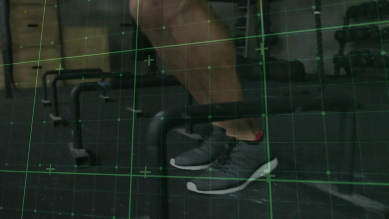 Vertical video: Nearing foot starting male lower legs hopping over gym bars for workout, green grid