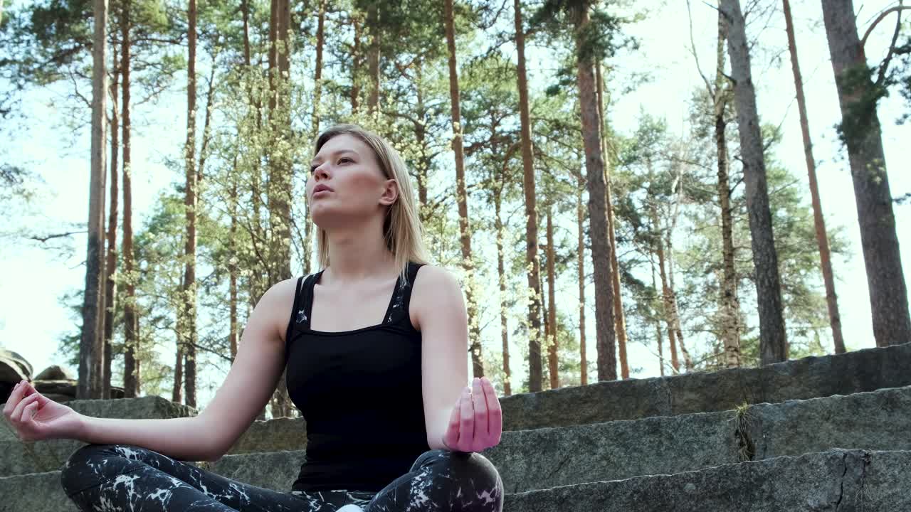 una mujer meditando en un bosque.